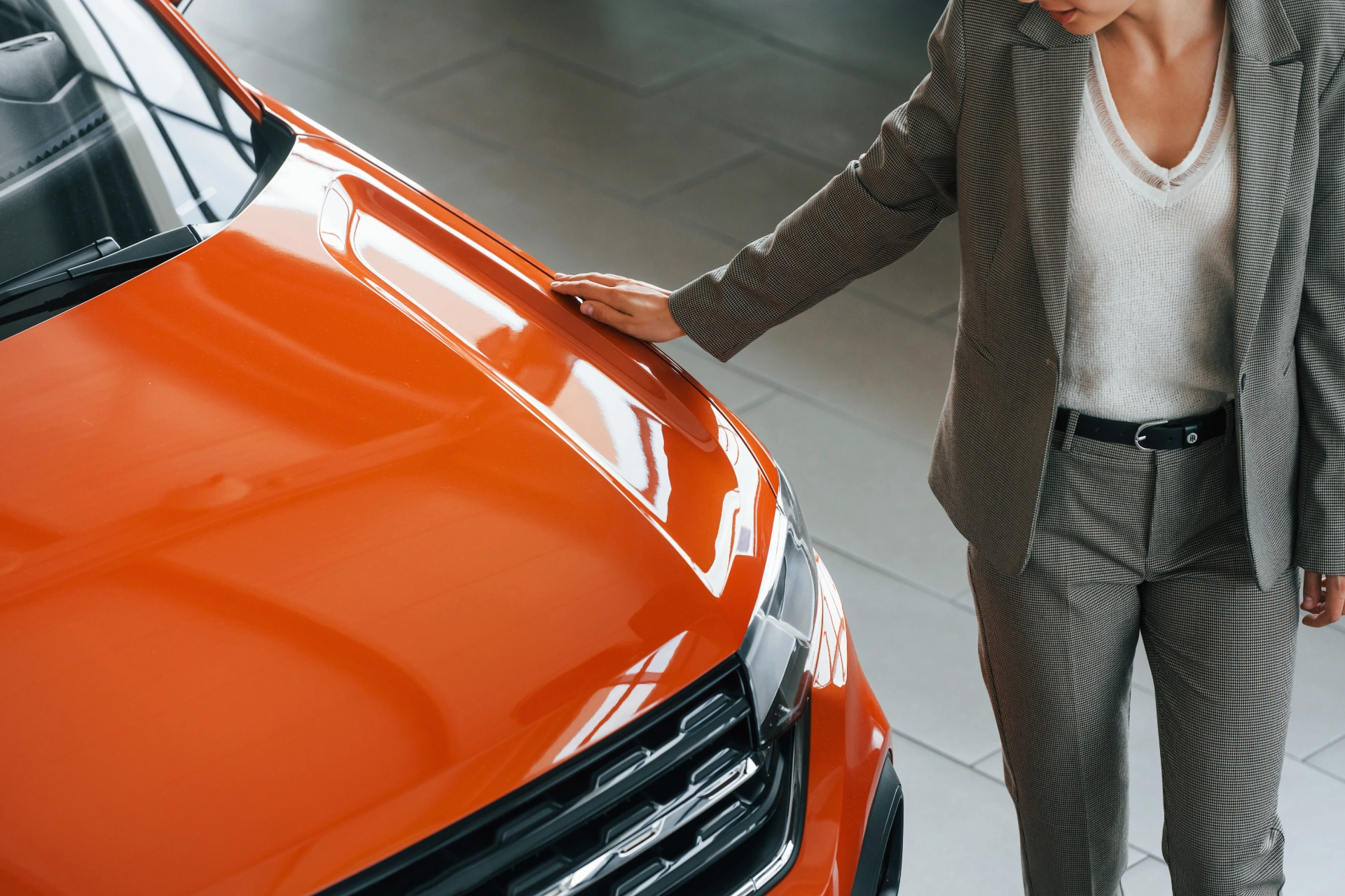 woman-standing-near-orange-colored-car-and-touchin-2023-11-27-05-00-23-utc
